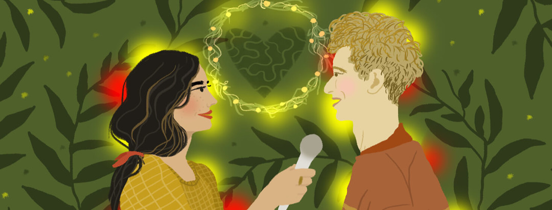A woman interviews her husband under a wreath with a heart inside; leaf sprigs and flashing lights surround them.