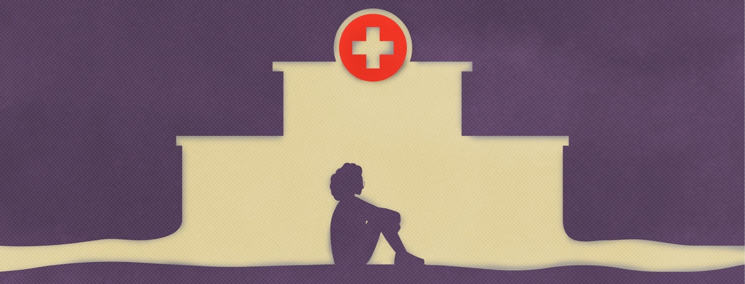 A woman sits in a fetal position in the cutout shape of a hospital building